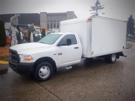 A white 2012 Dodge Ram 3500 truck with a box cargo area is parked with a single cab and wide wheels