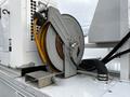 A metal hose reel with yellow and black hoses attached on top of a white vehicle