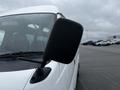 A 2002 Nissan Van with a focus on the driver's side rearview mirror showing raindrops on its surface