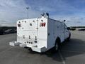 A white 2017 Ford F-350 SD with a utility body and multiple lights mounted on the roof and rear of the truck