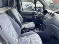 Interior of a 2013 Ford Transit Connect showing two front seats with patterned upholstery and a dashboard with controls and a gear shift