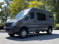 A 2017 Mercedes-Benz Sprinter in gray with large windows and a high roof design showcasing a modern van style with off-road tires