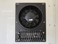A black cooling fan mounted on a white surface with a protective metal grille and a label attached to the fan