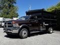 2015 RAM 5500 dump truck with a brown cab and black dump bed parked on a surface with visible wheels and side view mirrors
