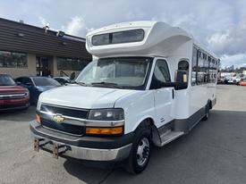 A 2018 Chevrolet Express, a white passenger van with a high roof, large front grille, and side windows, is parked with the driver's door slightly open