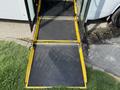 The image shows a wheelchair ramp extending from the entrance of a 2020 Chevrolet Express, featuring a textured black surface and yellow safety markings