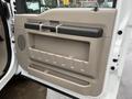Interior door panel of a 2008 Ford F-350 featuring a beige finish with a black handle and multiple storage compartments