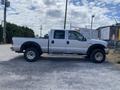 A silver 2007 Ford F-350 Super Duty pickup truck with a crew cab and large tires parked on gravel