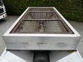 A 2011 Ford F-550 with a flatbed and metal grate on top showing signs of rust and wear