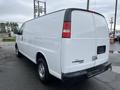 A white 2014 Chevrolet Express van with a high roof and rear doors ajar showing a blank rear license plate area