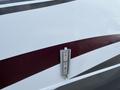 A close-up of a silver latch on a white and maroon exterior of a 2013 Outdoor Wind River camper