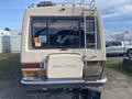 A 1987 Chevrolet Fleetwood Pace Arrow recreational vehicle with a ladder attached to the rear and a sign displaying price information on the back window