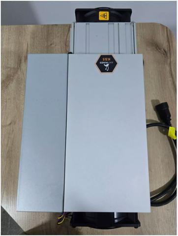 A Bitmain Antminer KS5 Pro mining machine in a box with a power cable connected on the side