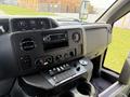 Dashboard of a 2010 Ford Econoline featuring knobs for climate control a radio display and various control buttons and switches