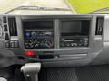 The dashboard of a 2018 Isuzu NRR featuring a stereo system control knobs and empty slots for additional equipment