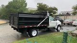 A 2021 International CV515 dump truck with a black bed and white cab parked on a wet surface