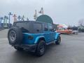 A blue 2020 Jeep Wrangler with a black hardtop and oversized tires parked at a lot