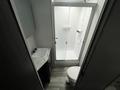 Inside a bathroom featuring a shower with herringbone tile, a compact vanity with a sink, and a modern toilet