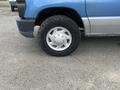 A blue 2010 Ford Econoline van with a visible tire featuring a silver wheel and rugged tread
