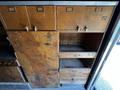 A wooden storage unit with multiple drawers and cabinet doors featuring metal handles and labels