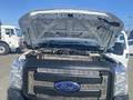 A 2014 Ford F-250 SD with the hood raised revealing the engine compartment and the Super Duty badge on the front grille