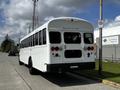 A 2022 Blue Bird BB Conventional school bus in white parked along a street with visible rear lights and a door labeled as an emergency exit