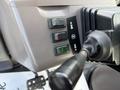 Control panel of a 2005 Case 570 featuring three buttons in red green and gray alongside a gearshift lever