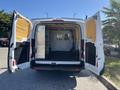 A 2016 Ford Transit van with its rear doors open revealing a spacious cargo area equipped with shelves and a security partition
