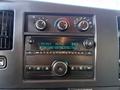 The dashboard of a 2015 GMC Savana featuring a radio display with FM station settings and control knobs for air conditioning and sound settings