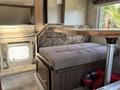 A seating area with a patterned cushion and a dining table in a travel trailer featuring wood accents and a window with curtains