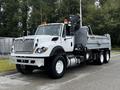 A 2017 International WorkStar 7600 truck with a silver dump bed and a black crane attachment on the back