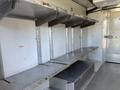 Interior shelving system of a 2019 Freightliner MT45 featuring multiple metal shelves attached to the wall with a lower storage compartment