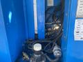 A close-up view of the internal mechanism and hydraulic components of a 1997 Genie S-65 4X4 featuring blue metal casing and various pipes and connectors