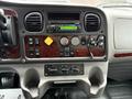 Dashboard of a 2017 Freightliner M2 106 featuring various dials switches and a radio with a wood grain panel