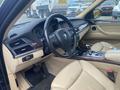 Interior of a 2009 BMW X5 featuring a leather steering wheel wooden trim and dashboard instruments alongside beige leather seats and a central control console
