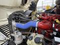 Close-up view of the engine compartment of a 2020 Freightliner M2 featuring a red intake manifold a blue silicone hose and various engine components and connectors