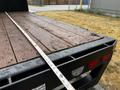 A 2020 Ford F-350 truck with a flatbed featuring wooden planks and a measuring tape laid across the bed surface