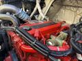 Close-up of a red engine with various hoses and wires visible including a prominent red valve cover labeled with the word Cummins