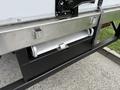 A storage compartment under the rear of a 2018 Hino 195 with a silver handle and metallic ramp extending from it