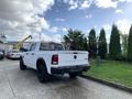 A white 2021 RAM 1500 truck with a black bed liner and large tires parked with the tailgate down