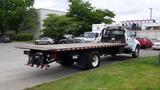 A 2008 Ford F-750 flatbed truck with a wooden loading surface and a black tow hitch parked in a lot