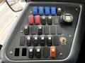 A control panel featuring multiple toggle switches and buttons including red and blue ones for various functions alongside a digital display and a key ignition slot