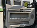 Interior door panel of a 2008 Ford F-550 featuring a storage compartment and speaker grilles
