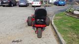 A 2014 Ferris Mower ISX 800 with a black seat and red body seen from the rear showcasing its large rear tires and suspension system