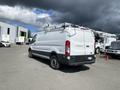 A white 2019 Ford Transit van with a ladder rack on the roof parked in a lot