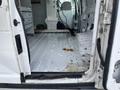 A 2008 Ford Econoline van with an open side door showing a clean yet slightly dirty interior cargo space with no visible seating and some debris on the floor