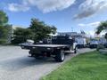 A 2013 Ford F-450 SD with a flatbed parked on a driveway surrounded by various vehicles