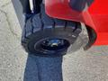 Close-up of a large, rugged tire on a red forklift with deep treads and a dark wheel rim showing a blue hubcap in the center