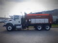 A 2016 International WorkStar 7500 truck with a large orange dump bed and dual rear wheels parked on a concrete surface