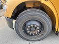 Close-up of a tire on a yellow 2007 Freightliner B2 showing the wheel rim and hub with visible tire tread marks and bolt patterns